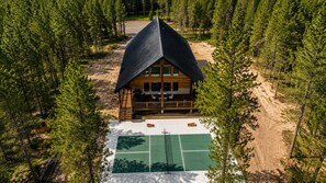 Une cabane avec un court de tennis devant, entourée d’arbres.
