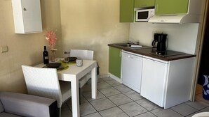 Uma cozinha compacta com micro-ondas, cafeteira e uma máquina de lavar louça pequena.