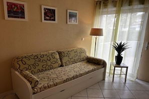Ein Wohnzimmer mit einer Couch, einem kleinen Tisch mit einer Pflanze und drei gerahmten Bildern an der Wand.