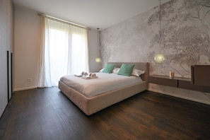 Ein Schlafzimmer mit einem Bett, einem Nachttisch, einer Wandlampe und einem Fenster mit Vorhängen.