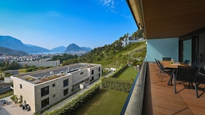 Ein modernes Gebäude mit Terrasse, Essbereich und Blick auf Stadt und Berge.