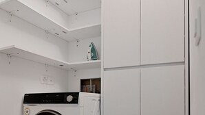 A laundry room with a washing machine, a dryer, and a tall white wardrobe. - Corba Luxury Lake View Apartment (Canobbio)