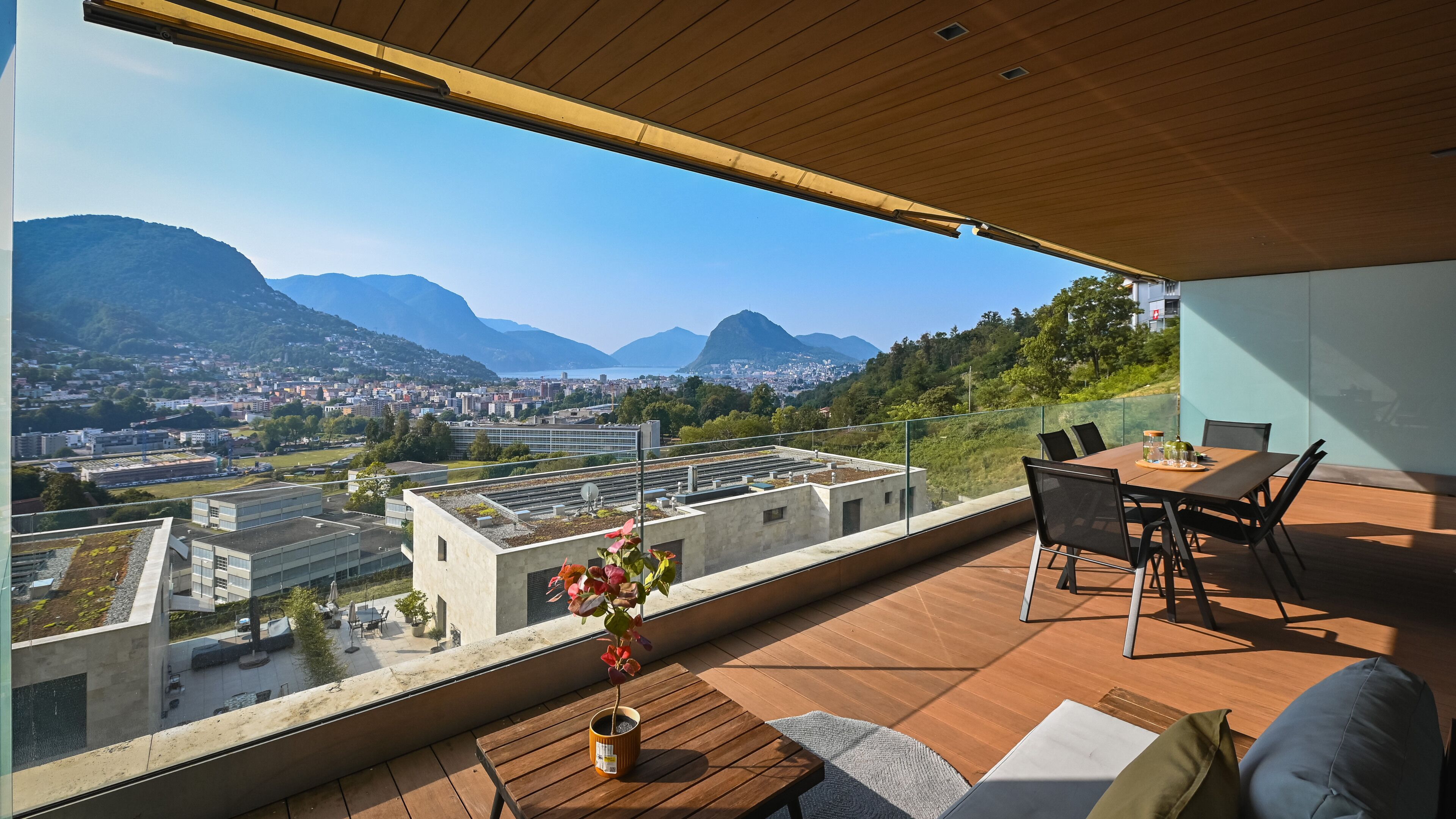 Un espace extérieur moderne, aménagé pour se détendre, avec vue sur le paysage urbain et les montagnes.