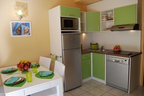 A compact kitchen with a refrigerator, microwave, and dishwasher.