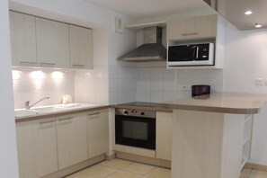 A kitchen with light-colored cabinets, a microwave, a stove, and a sink. - Apartment in Arcachon near Beach (Arcachon)
