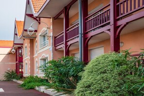 A multi-story building with balconies, a red door, and a well-maintained garden. - Apartment in Arcachon near Beach (Arcachon)