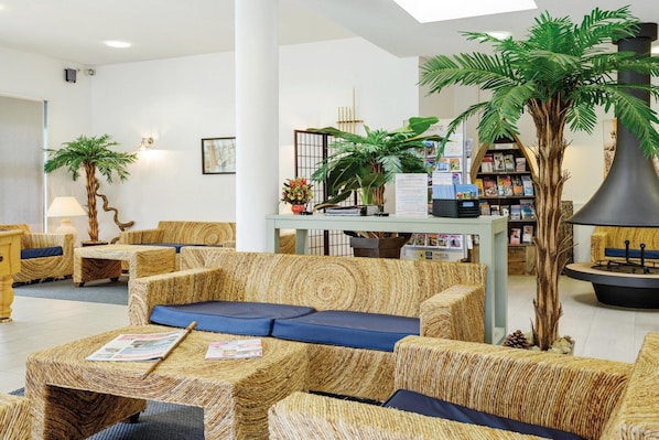 A lobby with wicker furniture, a reception desk, and a large potted plant.