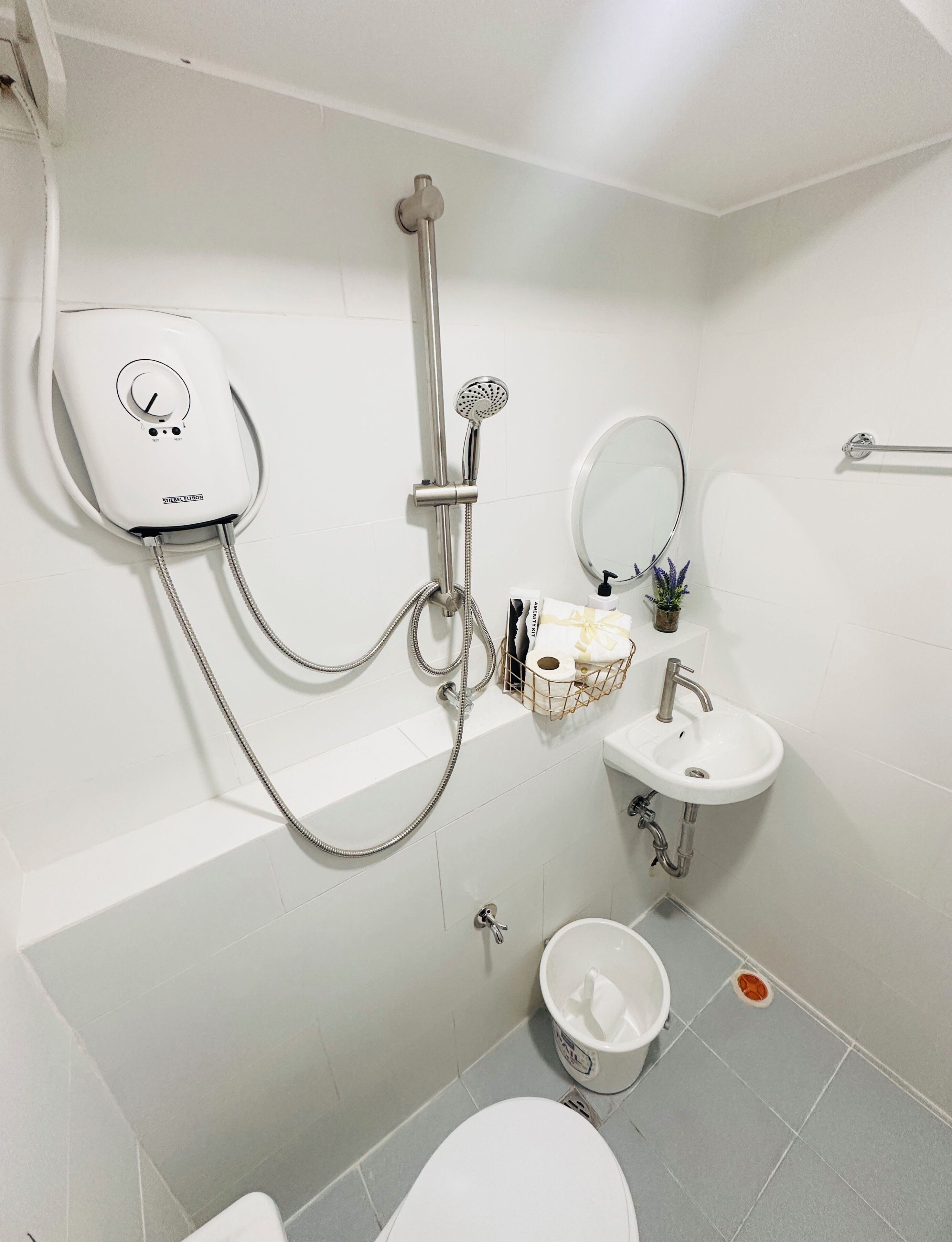 Un baño con ducha, inodoro, lavamanos y toallero.