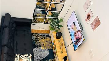 Un salon moderne comprenant un canapé d’angle, une table basse, un téléviseur et une étagère murale agrémentée d’objets décoratifs.
