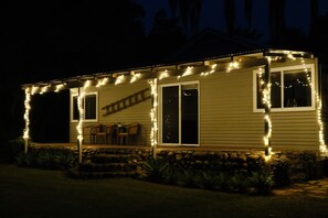 Una casa amb un porxo cobert, una paret de pedra de sostre i llums lluminoses.