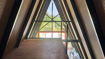 Une pièce triangulaire avec un plancher en bois et une grande fenêtre au fond.