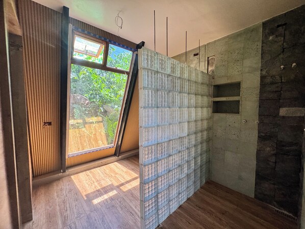 A room with a large window, a wooden floor, and a stone wall.