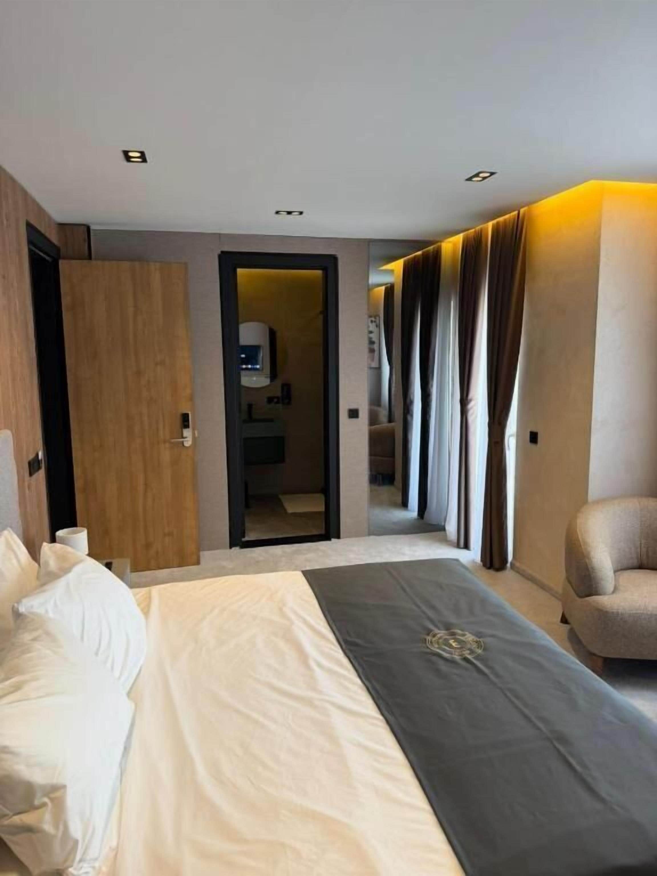 Una camera d'albergo con un letto, una sedia, una scrivania e un bagno visibile attraverso una porta aperta.