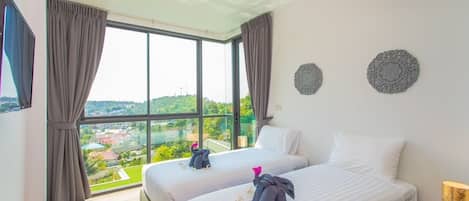 Habitación de hotel con dos camas, un ventanal grande y vistas a la ciudad.