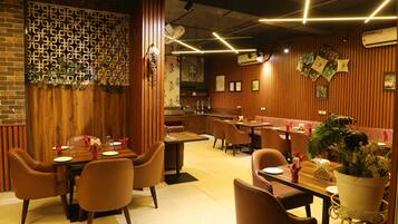 Un interno ristorante con pannelli in legno, tavoli con sedie e un'area bar.