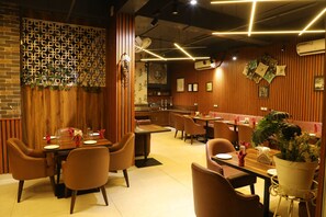 Interior de restaurante con paneles de madera, mesas con sillas y una zona de bar.