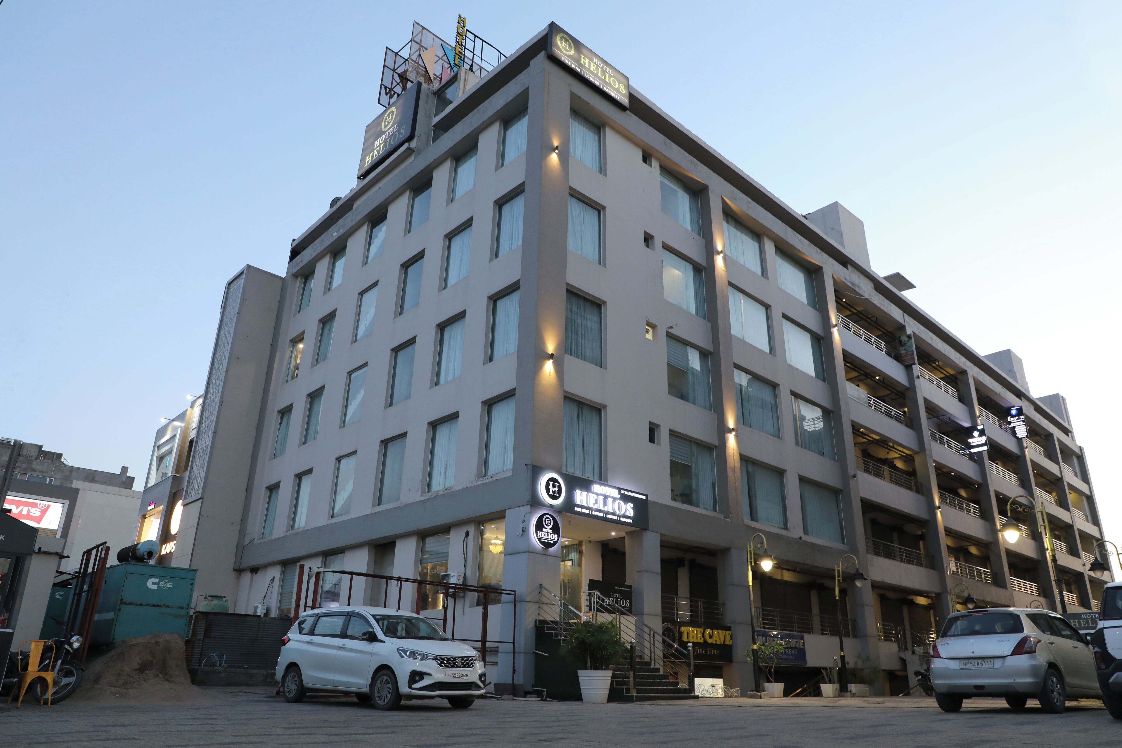 Ein mehrstöckiges Hotel mit einem gut sichtbaren Schild für Hotel Helios, das ein modernes architektonisches Design mit flachem Dach und großen Fenstern aufweist.