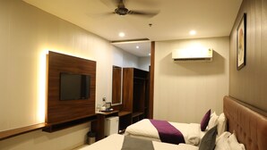 Habitación de hotel con cama, televisor, escritorio, armario y aire acondicionado.