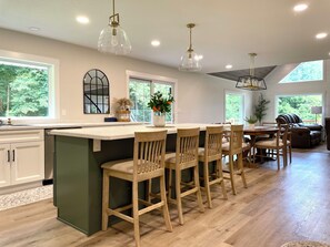 A modern kitchen with a central island, wooden bar stools, and pendant lighting. - Wooded Family Escape | Grill | DiscGolf | Big Yard (Plymouth)