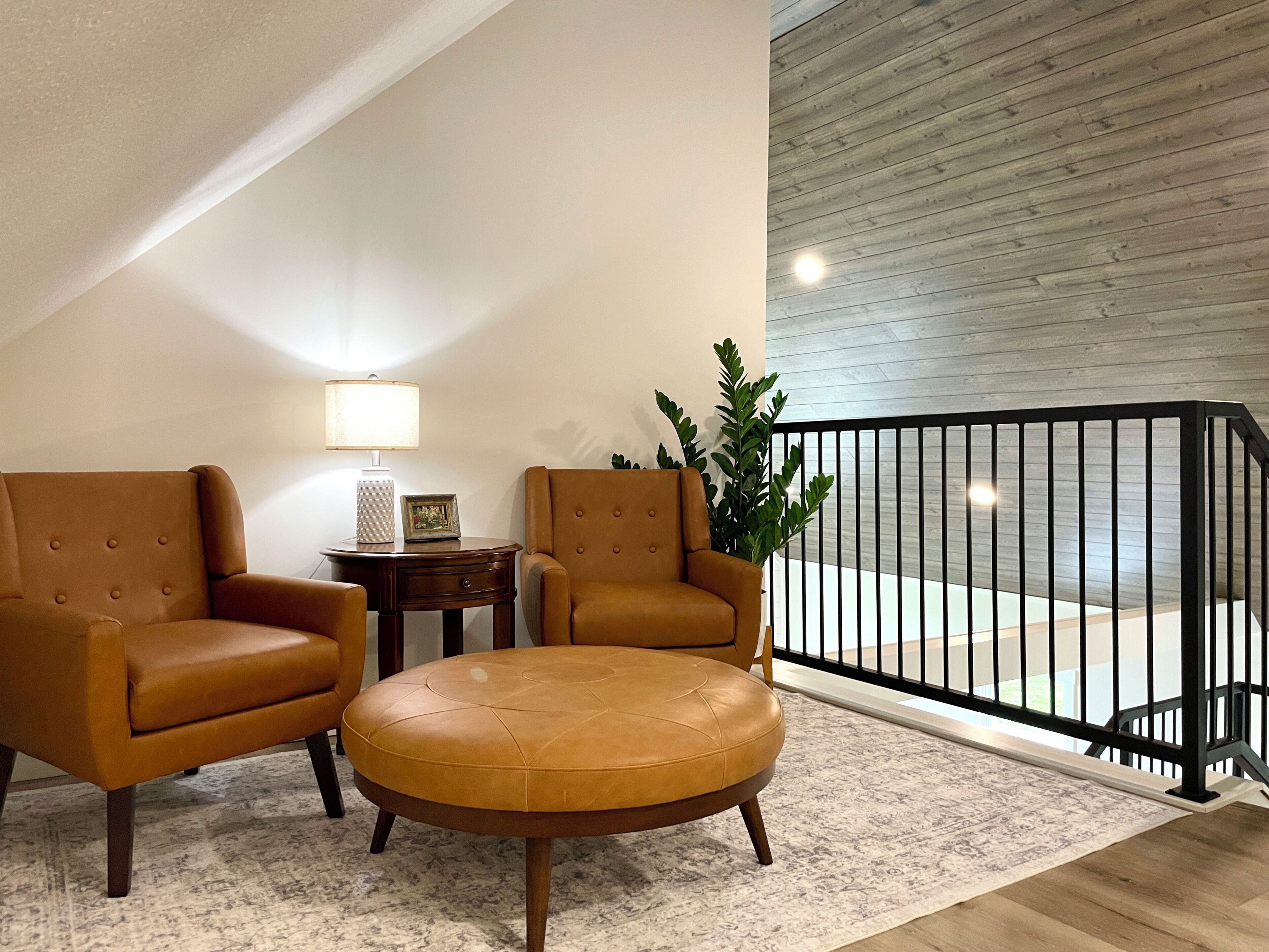 A modern living room with two leather armchairs, a small side table, a lamp, and a potted plant.