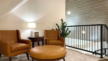 A modern living room with two leather armchairs, a small side table, a lamp, and a potted plant.
