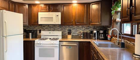 A modern kitchen with wooden cabinets, a stainless steel refrigerator, a built-in microwave, a gas stove, and a dishwasher.