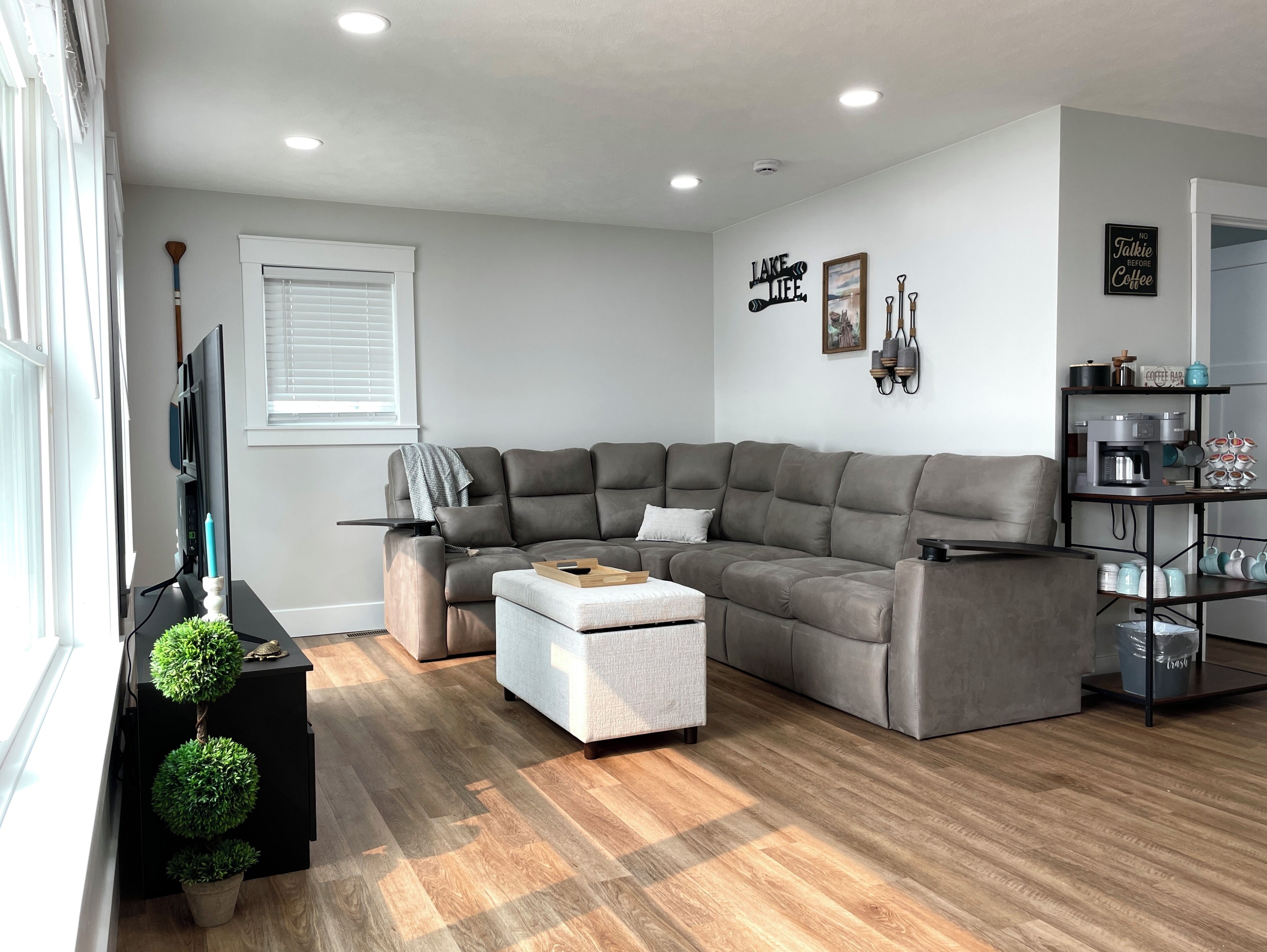 A modern living room with a sectional sofa, a coffee table, a television, and a bookshelf.