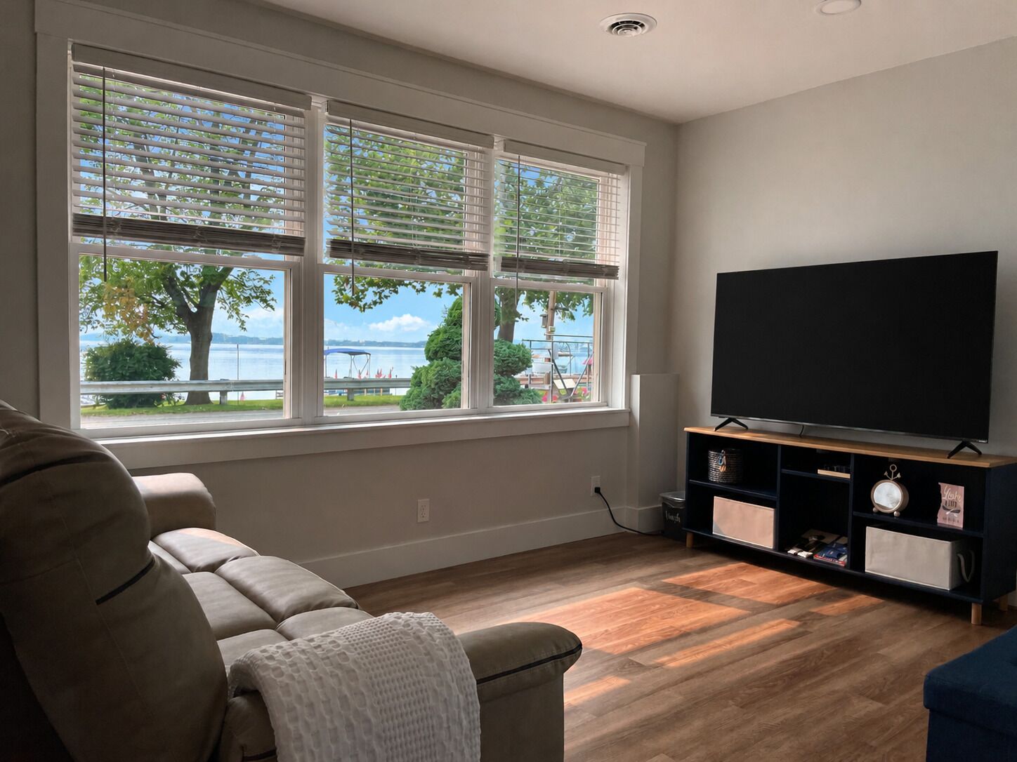 A living room with a large window, a flat-screen TV, a sofa, and a wooden floor.
