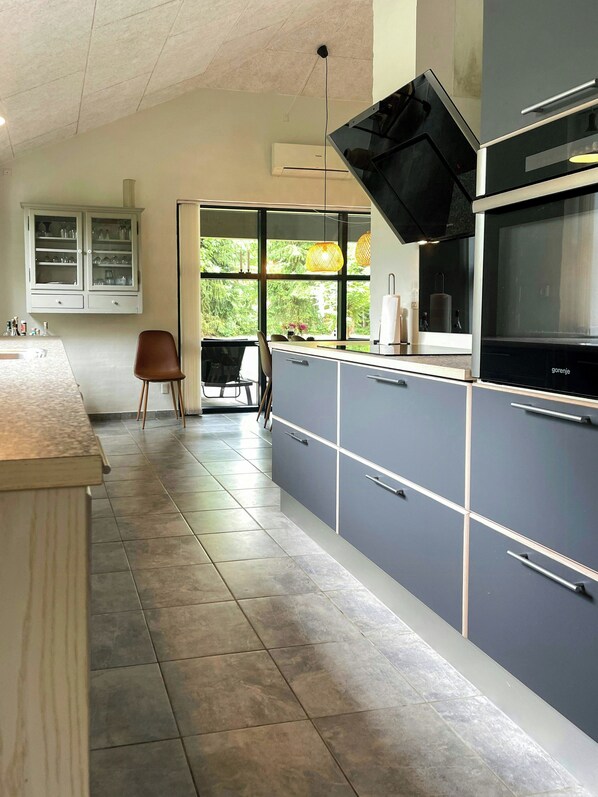 A modern kitchen with grey cabinets, a black oven, and a window with a view of greenery.