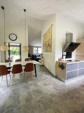 A spacious kitchen with a dining area, a large map on the wall, and a clock.