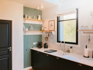 A kitchen with dark cabinets, a white countertop, a window with a view, and a sink with a faucet. - Ker Paravel · Family villa · Beach 4 min · Garden (Saint-Lunaire)