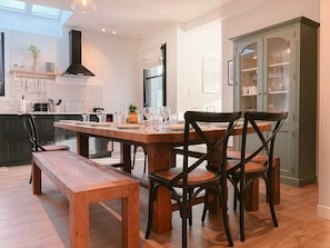 A modern kitchen with a dining table, chairs, and a bench. There is a cabinet with glass doors and a hanging light fixture. - Ker Paravel · Family villa · Beach 4 min · Garden (Saint-Lunaire)
