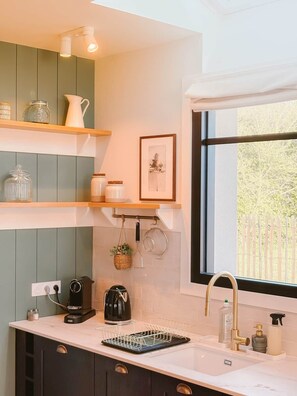 A modern kitchen with a built-in oven, a coffee maker, and a sink with a gold faucet.