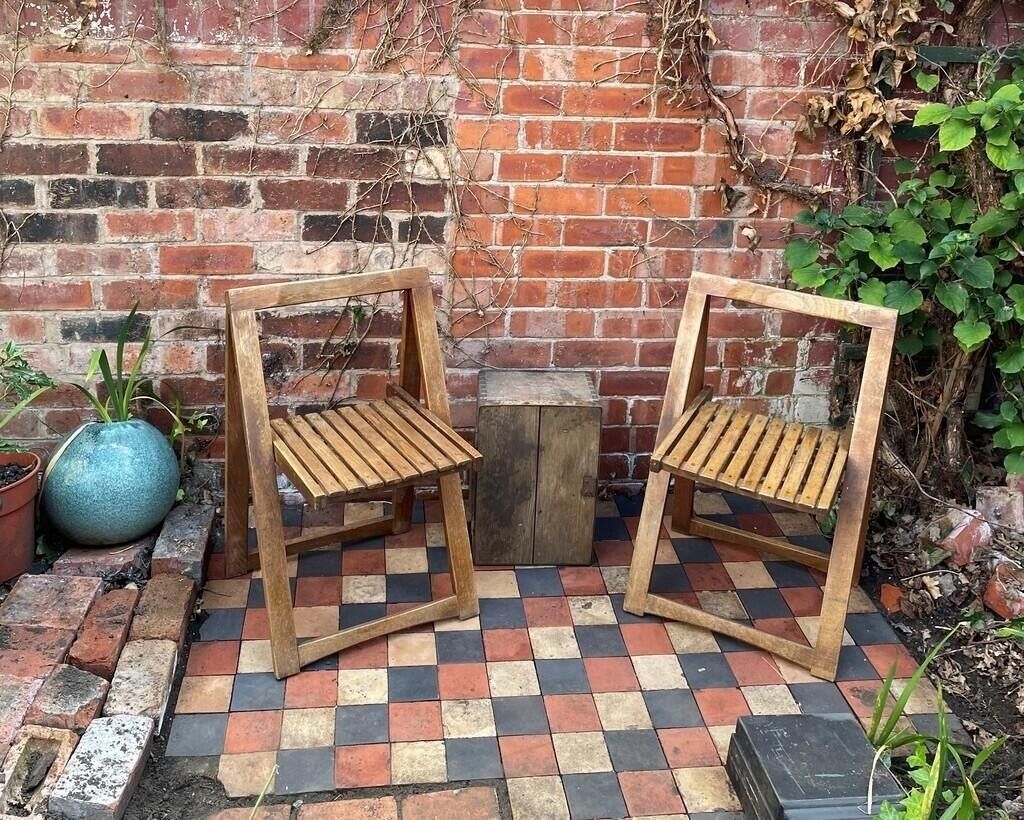 Two wooden chairs with slatted seats and backs, placed on a checkered tile floor.