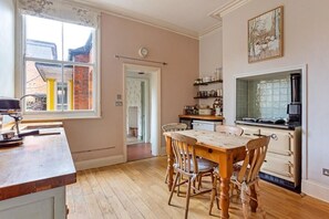 A kitchen with a wooden table and chairs, a stove, and a window with a view of a building outside.