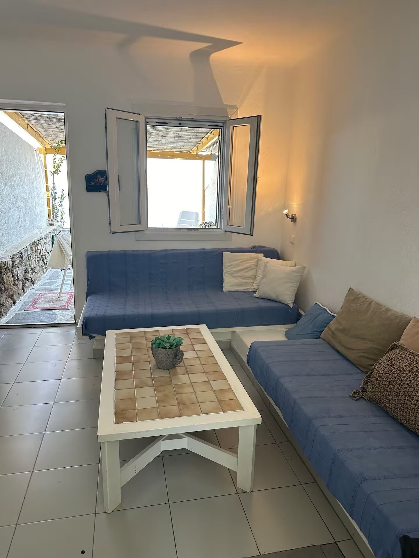 A room with a blue sofa, a white coffee table, and a potted plant.