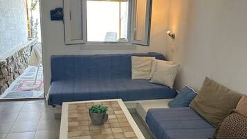 A room with a blue sofa, a white coffee table, and a potted plant.