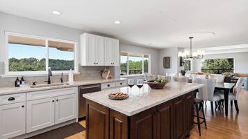 A modern kitchen with a large island, white cabinetry, and a view of the outdoors.