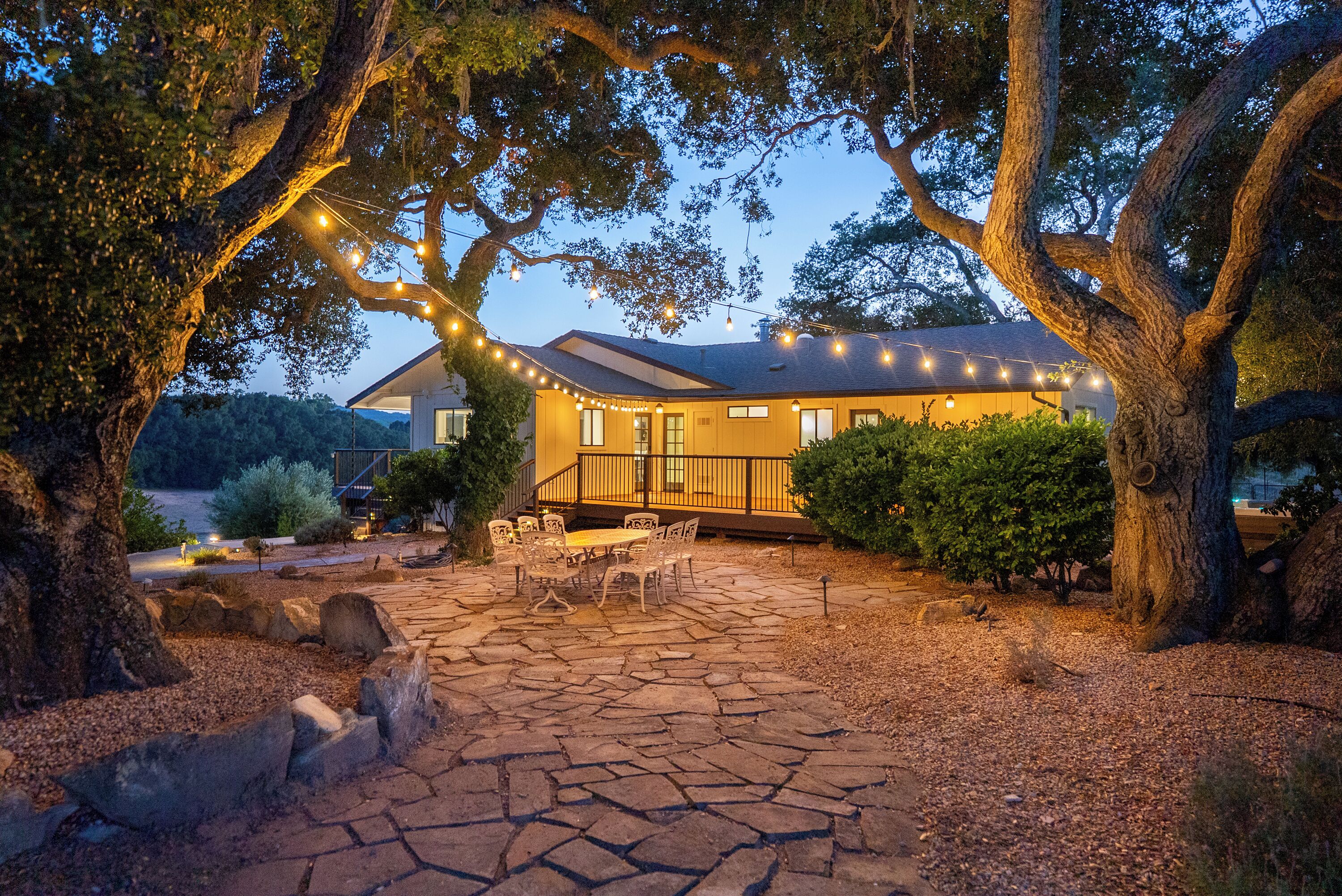 A house with a stone patio, outdoor furniture, and string lights.
