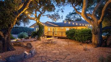 A house with a stone patio, outdoor furniture, and string lights.