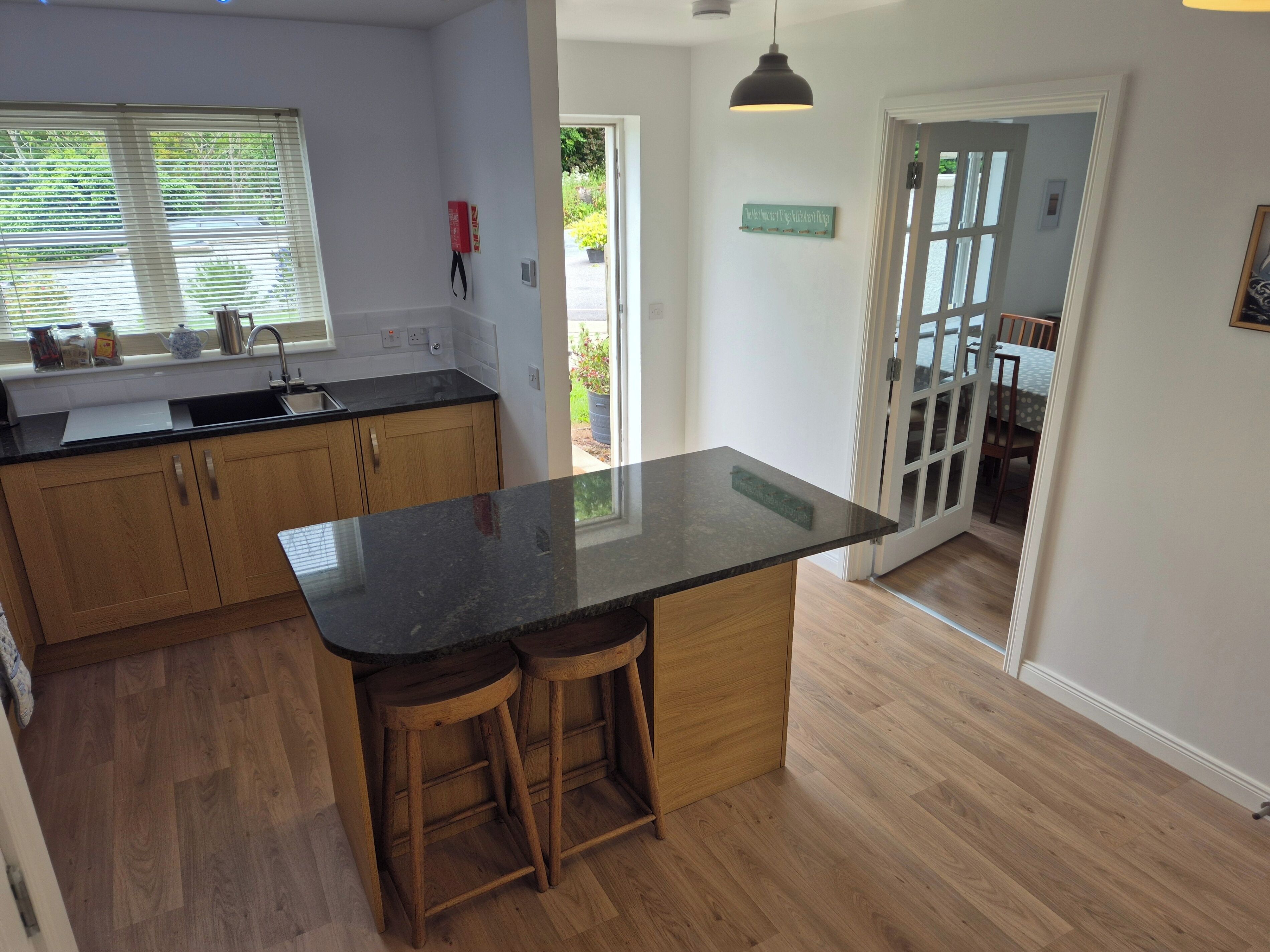 A kitchen with wooden cabinets, a black countertop, and two stools.