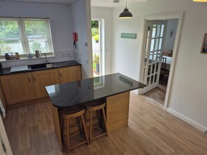 A kitchen with wooden cabinets, a black countertop, and two stools.