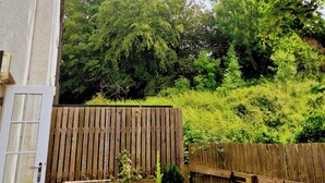 A wooden fence, potted plants, and a house with a window. - 2 Bed House - Sleeps 4 - Pets - Parking - Beach (Cromarty)