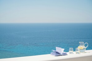A seaside view with a table holding a book, glasses, and a teapot. - Vrachos Retreats Sunset Sea View Villa - 3BR (Mykonos)