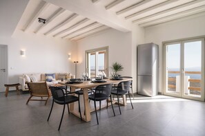 Een moderne keuken met een eethoek, grote ramen en uitzicht op zee.
