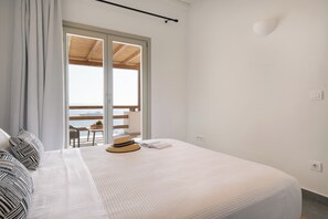 A bedroom with a bed, a window, and a view of the sea. - Vrachos Retreats Sunset Sea View Villa - 3BR (Mykonos)