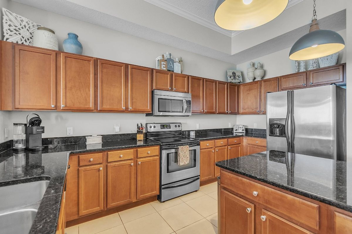 A kitchen with wooden cabinets, a stainless steel refrigerator, a microwave, and a stove.