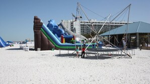 Ein aufblasbarer Wasserpark mit Rutschen und Klettergerüsten an einem Sandstrand.