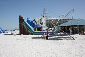 Ein aufblasbarer Wasserpark mit Rutschen und Klettergerüsten an einem Sandstrand.