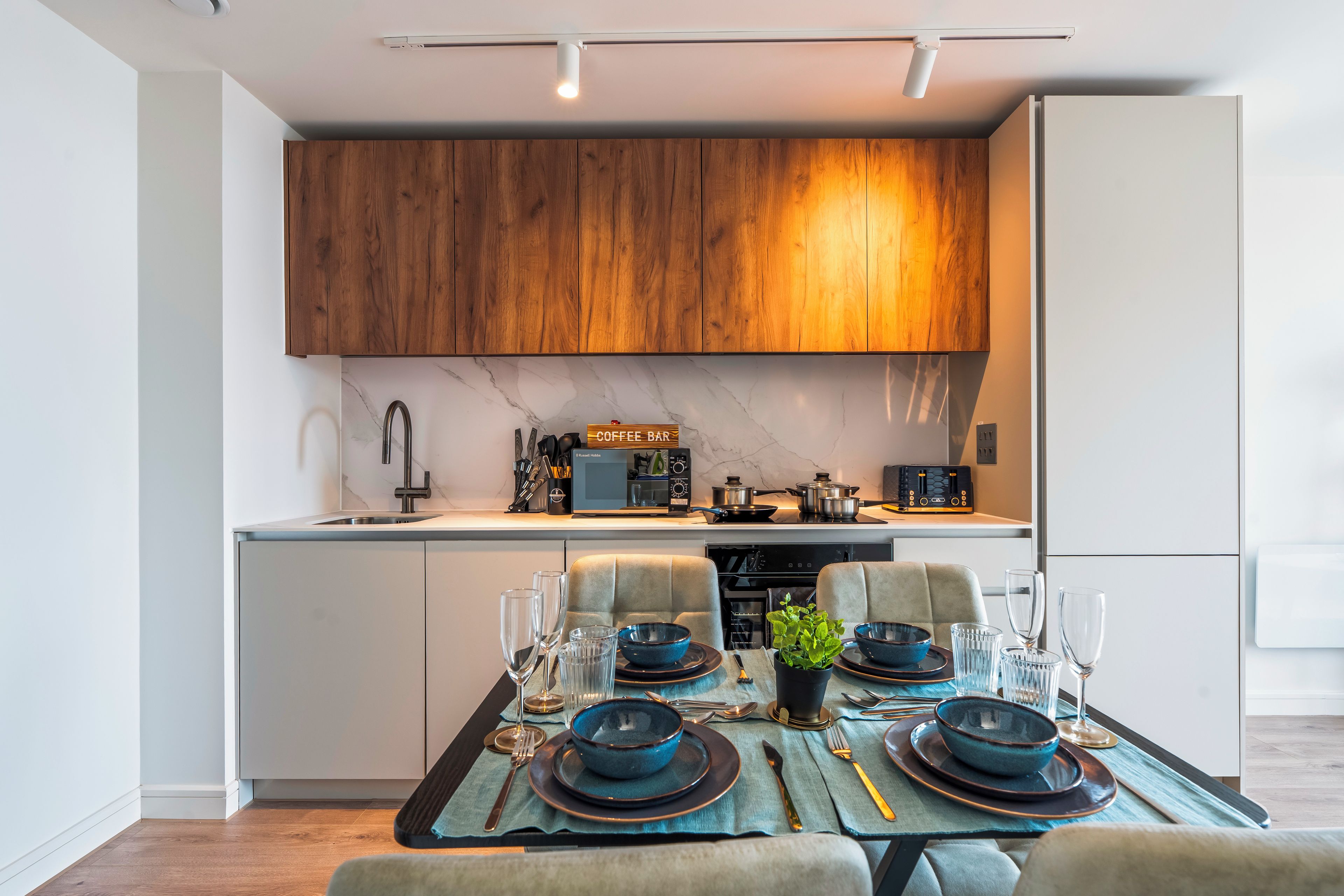 Una cocina moderna con armarios de madera, horno empotrado y comedor listo para una comida.